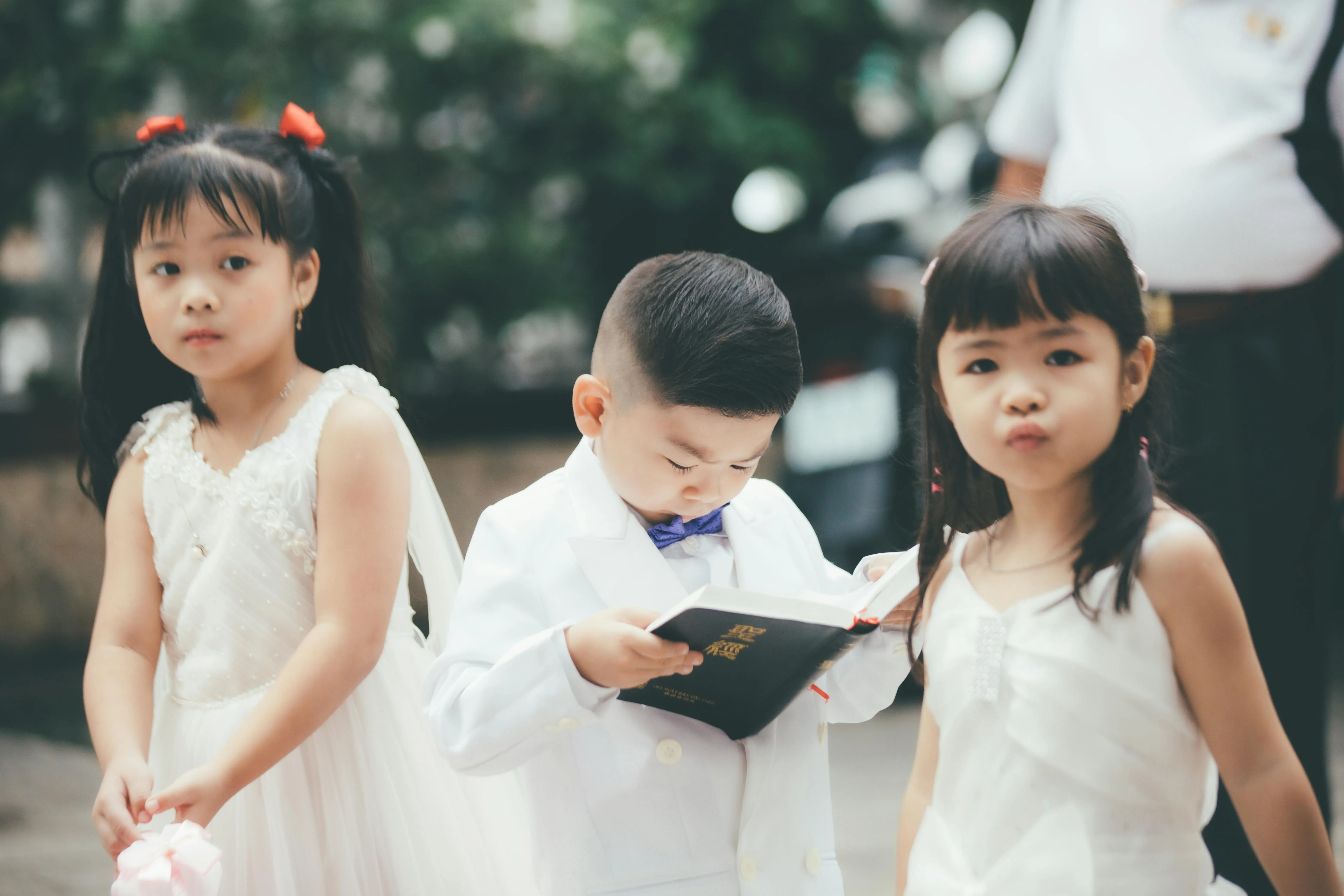 Huynh Van on A Boy in White Clothes Holding a Book While Standing Beside the Girls
