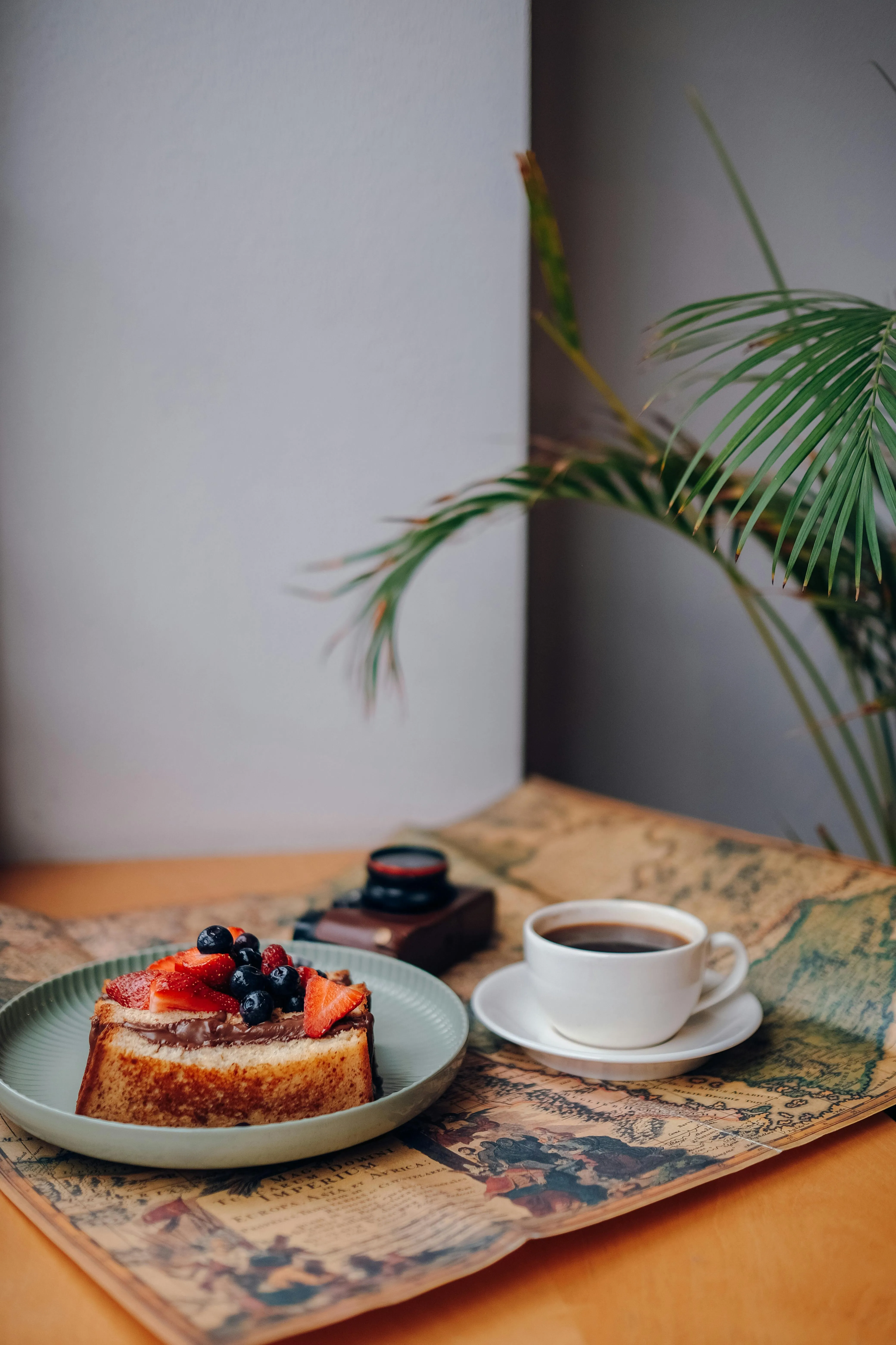 A cup of coffee next to a slice of cake on a plate