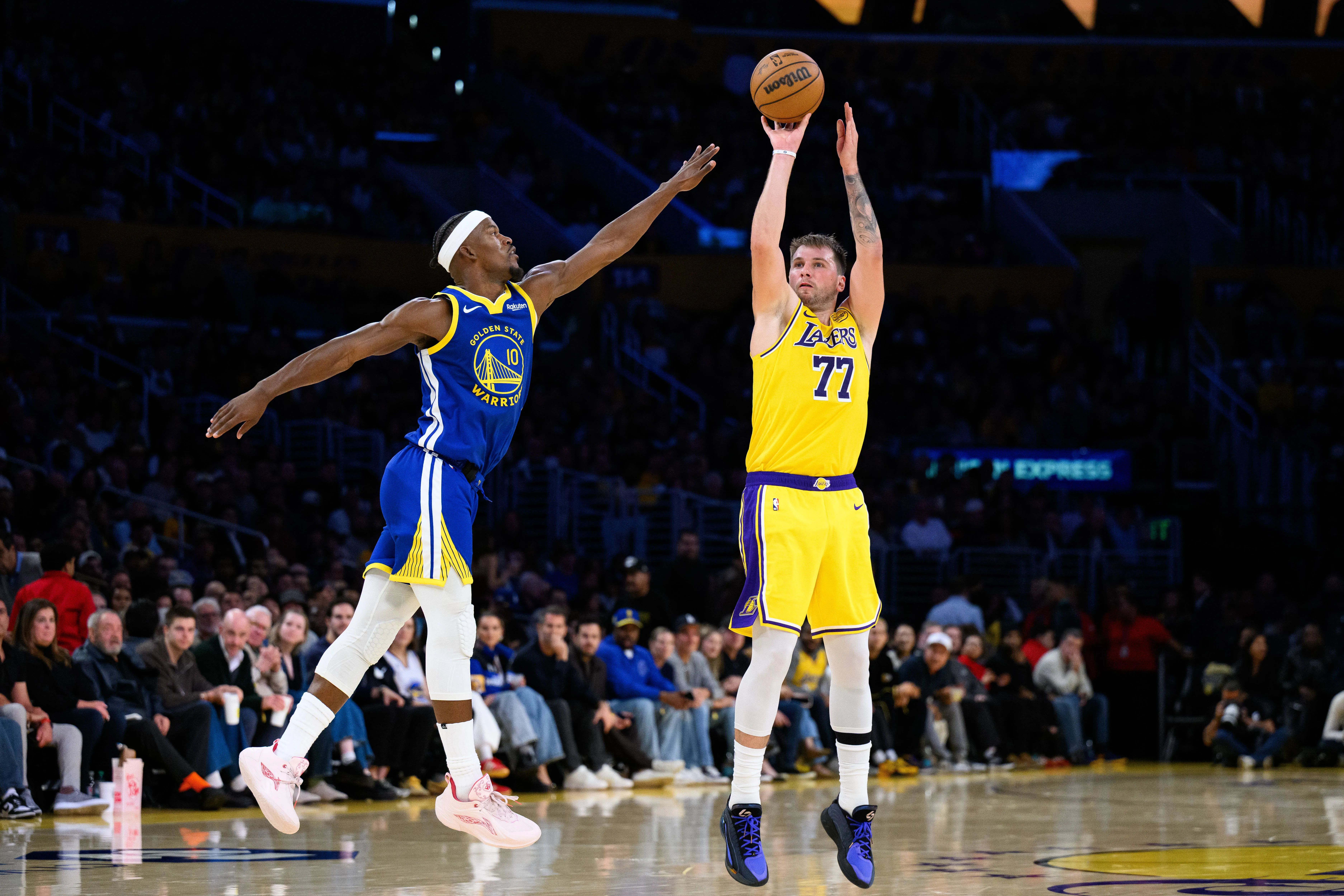 Oct 21, 2025; Los Angeles, California, USA; Los Angeles Lakers guard Luka Doncic (77) shoots over Golden State Warriors forward Jimmy Butler III (10) during the first half at Crypto.com Arena.
