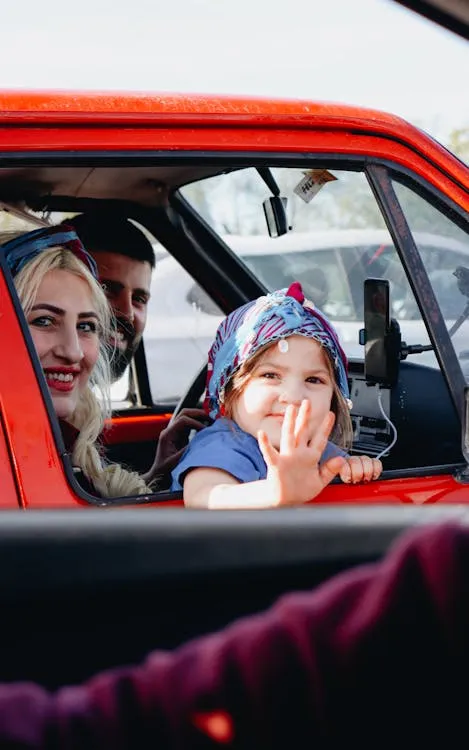 family sitting inside a 1960s car without visible seatbelts