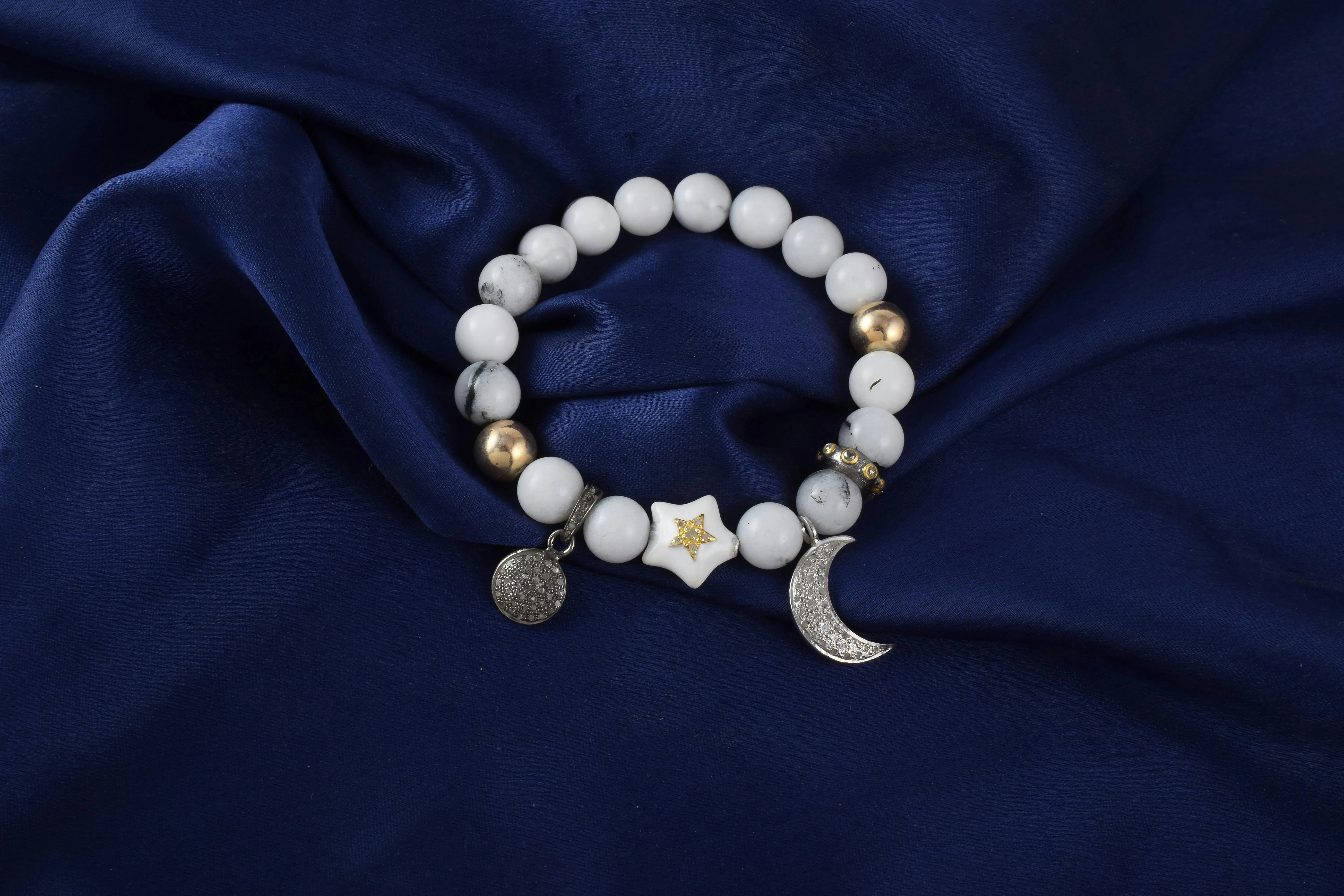 A silver charm bracelet with various small hanging pendants on Pexels