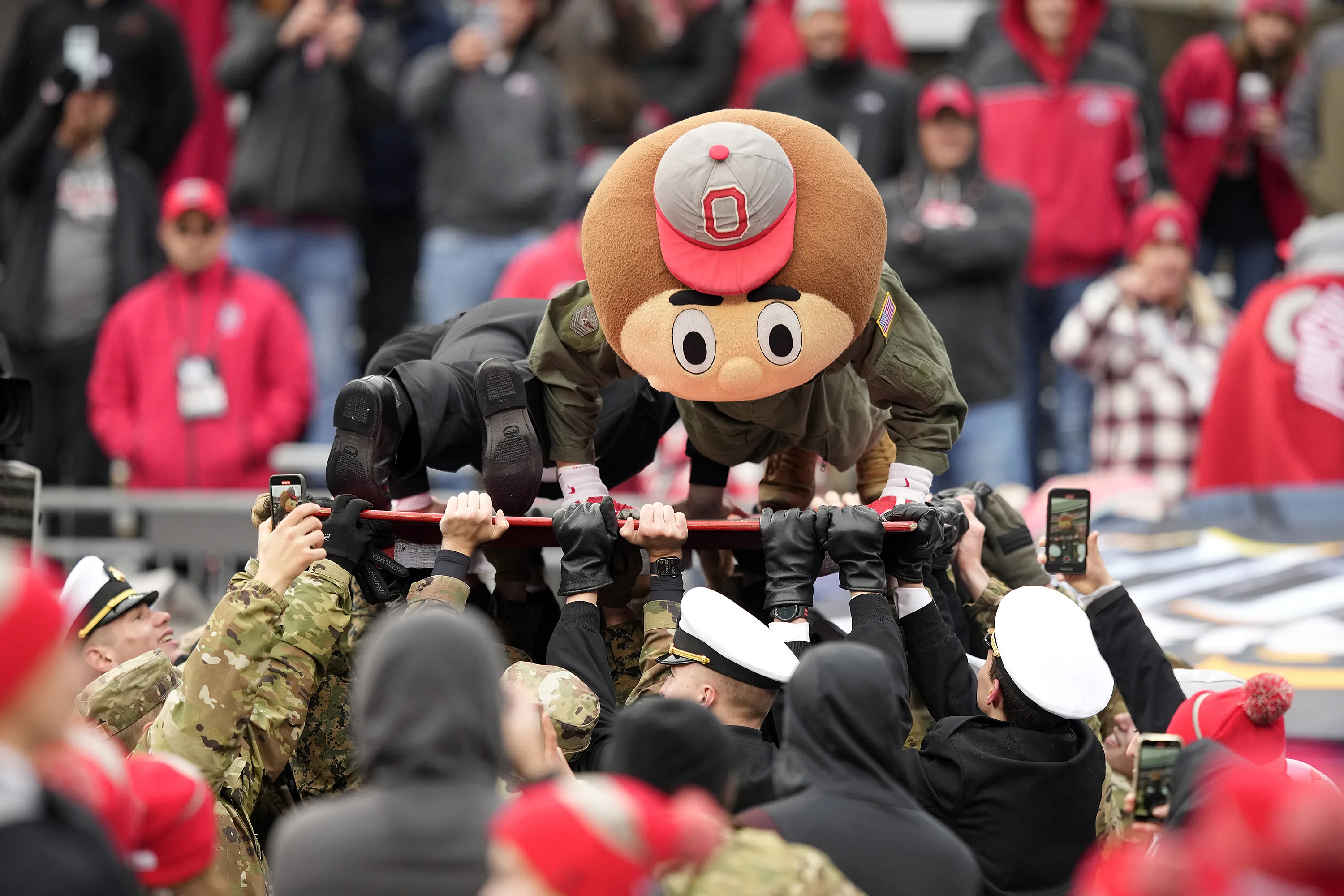 People lifting up men in army mascot